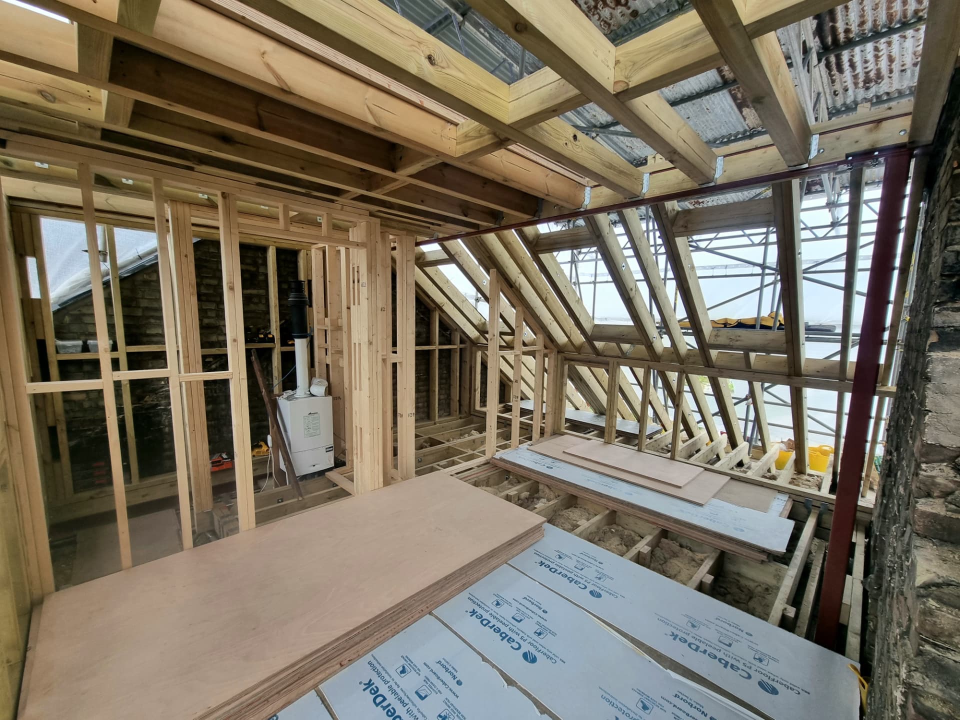 Loft conversion under construction, with timber roof framing and new floor boards being laid