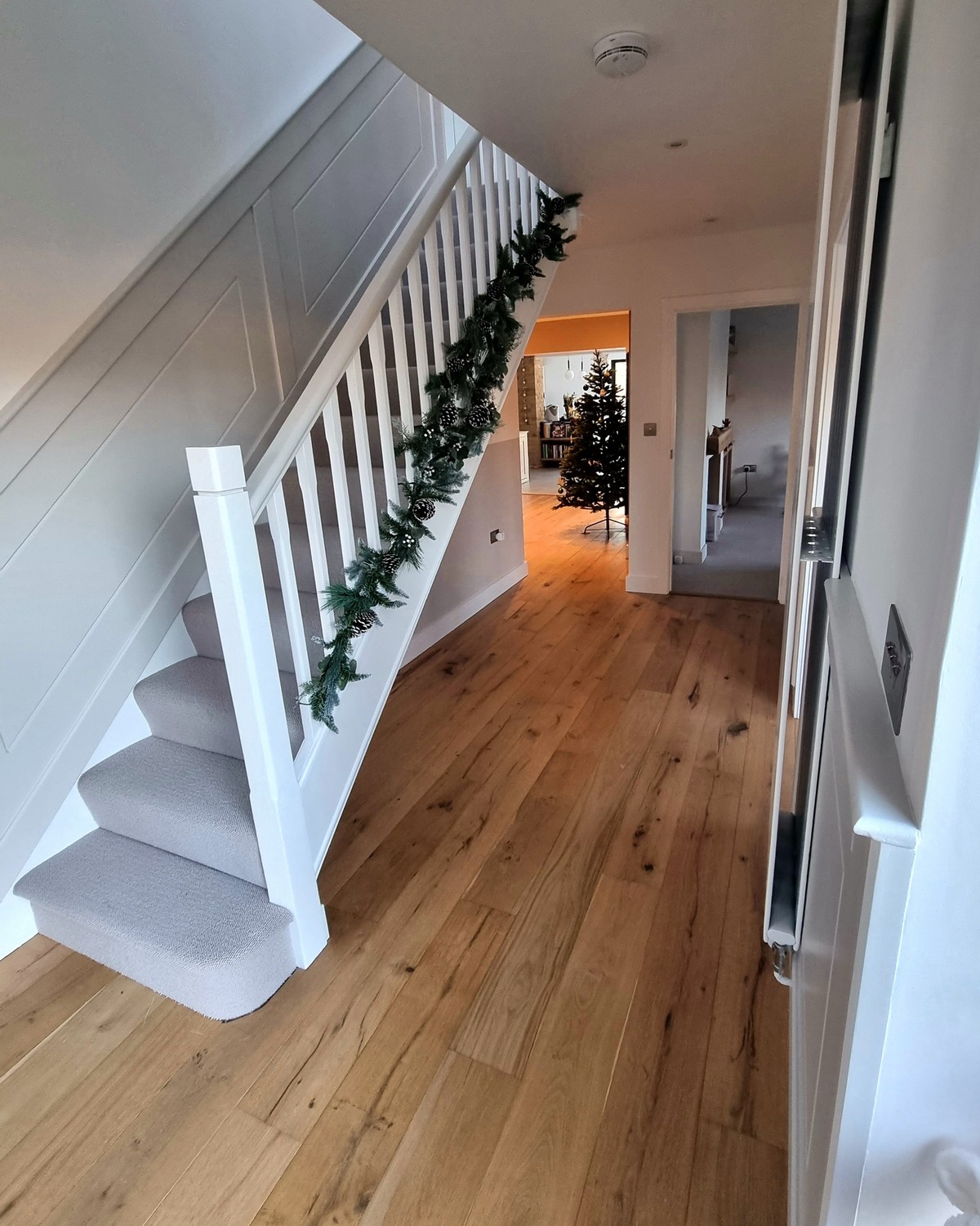 Hallway with wide-plank oak flooring, a painted staircase, and fitted skirting and architraves