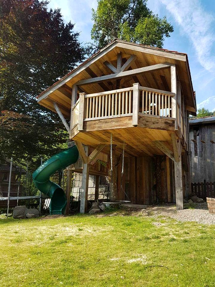 Treehouse seen from the lawn, showing the roof trusses, balcony and spiral slide